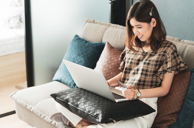 Jovem mulher asiática usando cartão de crédito para fazer compras online