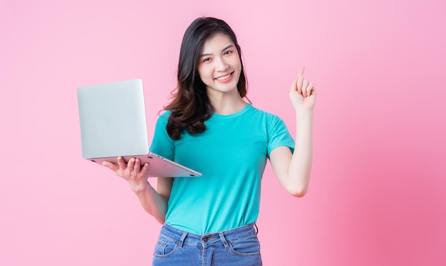 Jovem mulher asiática usando laptop em fundo rosa