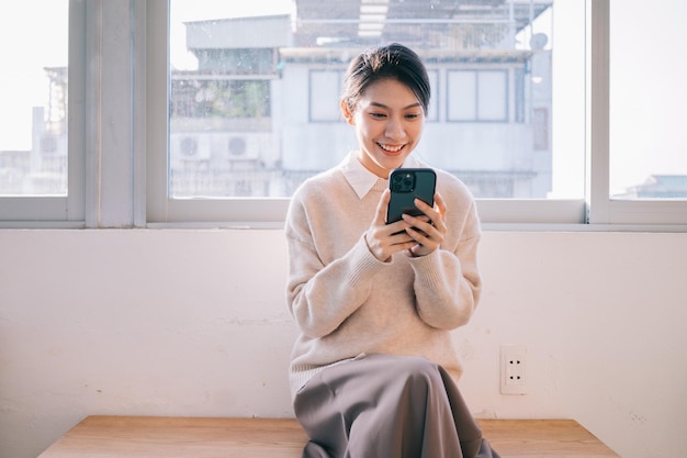 Jovem mulher asiática usando smartphone em casa