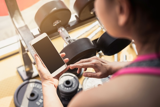 Foto jovem mulher asiática usando smartphone no ginásio