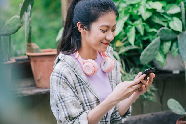 Jovem mulher asiática usando smartphone no jardim