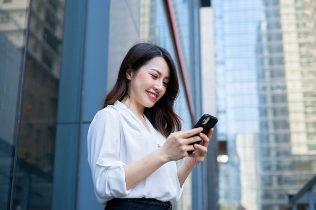 Jovem mulher asiática usando smartphone para enviar mensagens de texto para as amigas