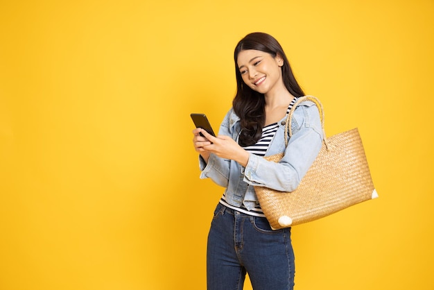 Foto jovem mulher asiática usando smartphone sobre fundo amarelo
