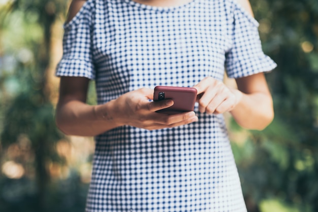 Jovem mulher asiática usando telefone celular natureza ao ar livre