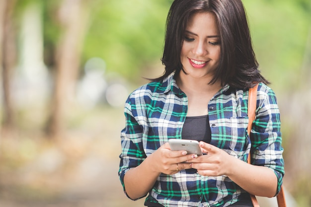 Jovem mulher asiática usando um telefone celular enquanto caminhava no parque