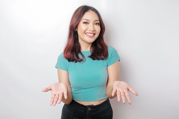 Jovem mulher asiática vestindo camisa azul apresentando uma ideia enquanto olhava sorrindo em fundo branco isolado