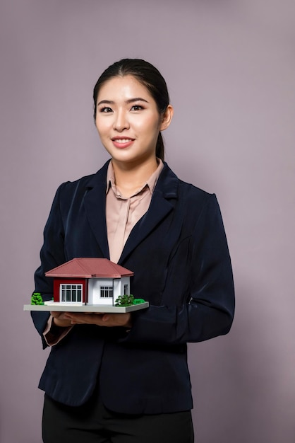 Jovem mulher asiática vestindo terno formal segurando modelo de casa Entusiasmado