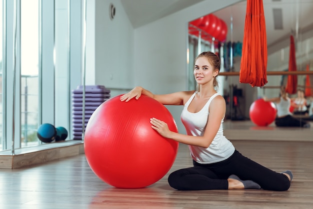 Jovem mulher atlética fazendo exercícios com bola de fitness no ginásio