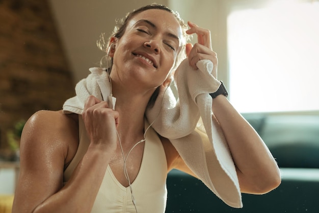 Foto jovem mulher atlética sorridente limpando o suor do rosto com uma toalha