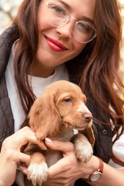 Jovem mulher atraente abraça um cachorrinho fofo de cocker spaniel. um novo membro fofo da família. cuidados com animais de estimação e conceito de animais de estimação