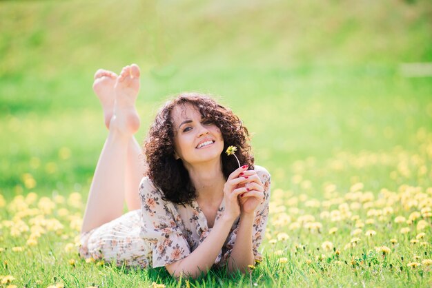 Jovem mulher atraente, com cabelos longos encaracolados, posando no jardim primavera florescendo, macieiras