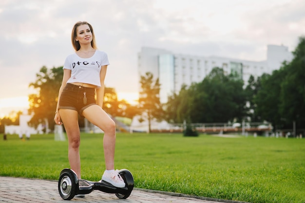 Jovem mulher atraente com hoverboard ao ar livre no parque ao pôr do sol. Tonificado