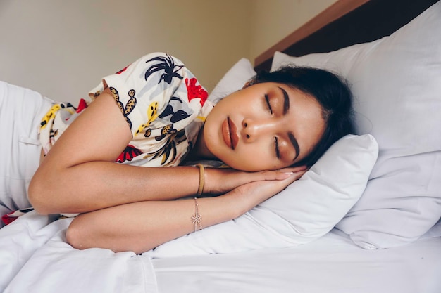 Jovem mulher atraente dormindo no quarto ela está deitada de lado e relaxando com os olhos fechados