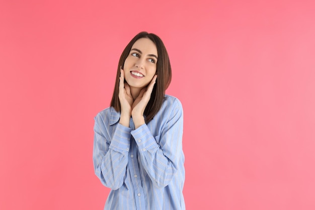 Jovem mulher atraente em uma camisa em fundo rosa