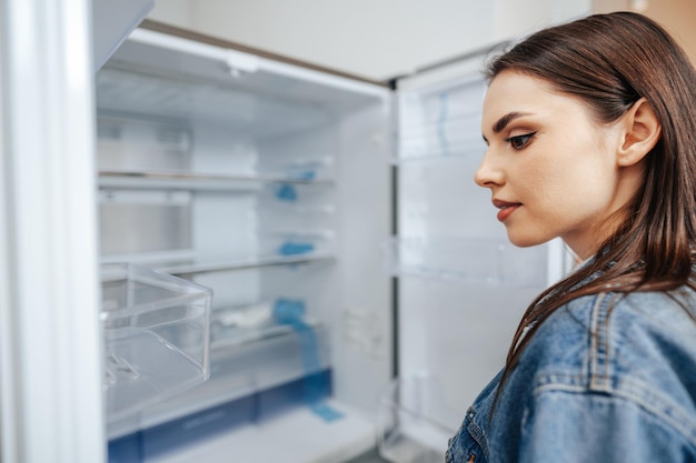 Foto jovem mulher atraente escolhendo geladeira em hipermercado