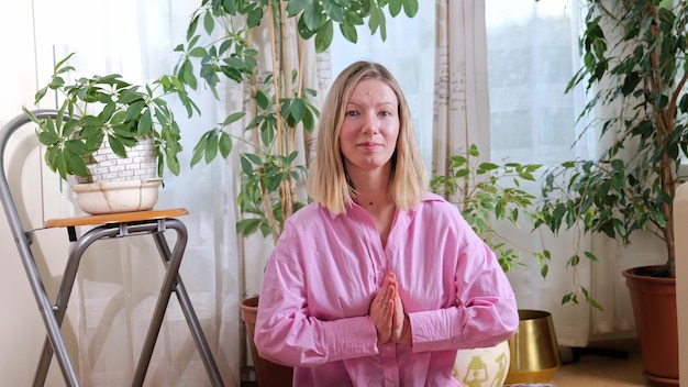 Jovem mulher atraente esportiva praticando ioga e meditação em casa, interior. conceito de calma
