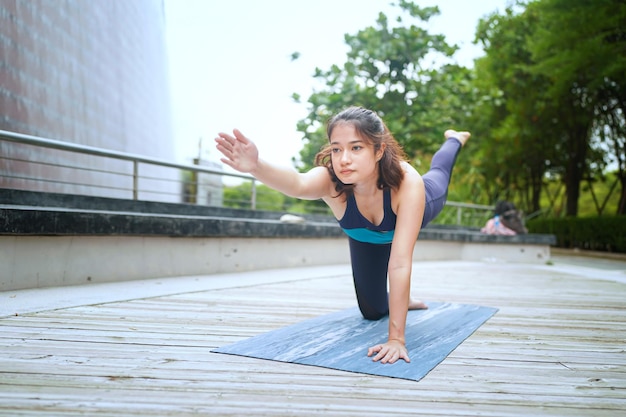 Jovem mulher atraente fazendo exercícios de ioga de alongamento no parque