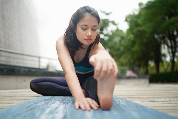 Jovem mulher atraente fazendo exercícios de ioga de alongamento no parque