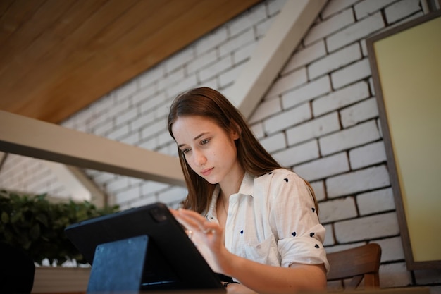 Jovem mulher atraente interagindo com o tablet móvel no café