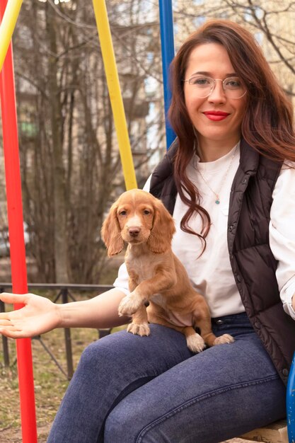 Jovem mulher atraente mostra um novo membro da família - um cachorrinho fofo de cocker spaniel. cuidados com animais de estimação e conceito de animais de estimação