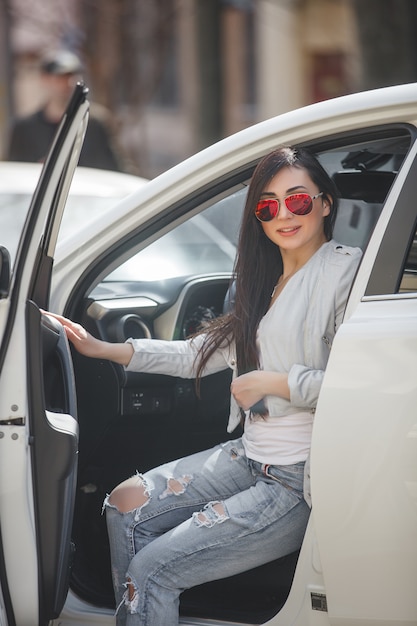 Jovem mulher atraente no carro. Mulher dirige um automóvel. Feche acima do retrato da mulher bonita ao ar livre. Senhora urbana.