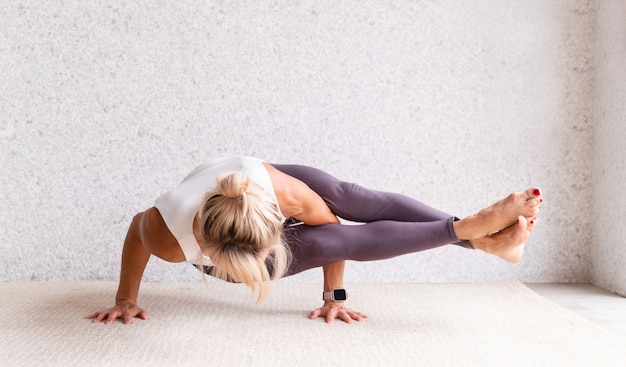 Jovem mulher atraente praticando ioga enquanto usa roupas esportivas dentro de casa