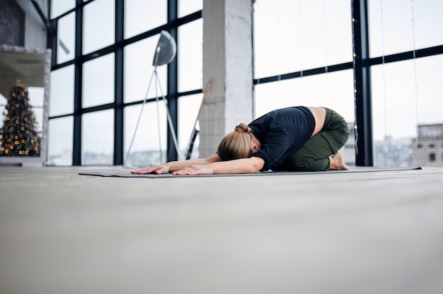 Foto jovem mulher atraente praticando ioga no estúdio loft