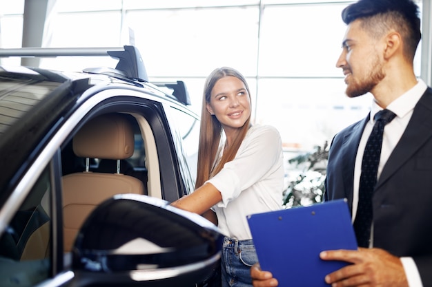 Jovem mulher atraente procurando um carro novo em um showroom