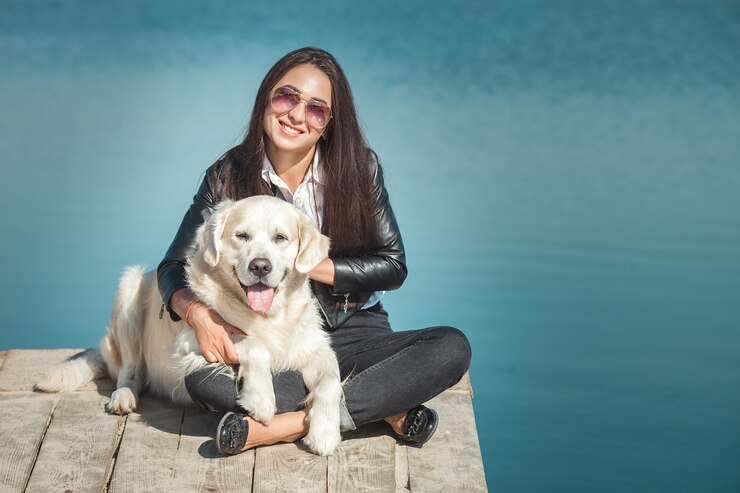 Jovem mulher atraente, sentado no píer com seu cachorro. Melhores amigos ao ar livre
