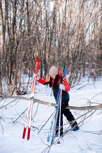 Jovem mulher atravessa floresta morena com agasalho de inverno caminha ao longo da estrada de neve e segura p ...