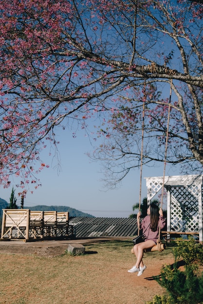 Jovem, mulher, balanço, parque, cor-de-rosa, trompete, árvores, flor