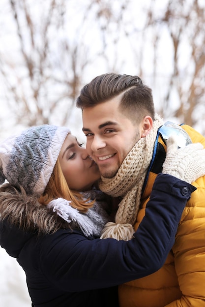 Jovem mulher beijando o namorado ao ar livre no inverno