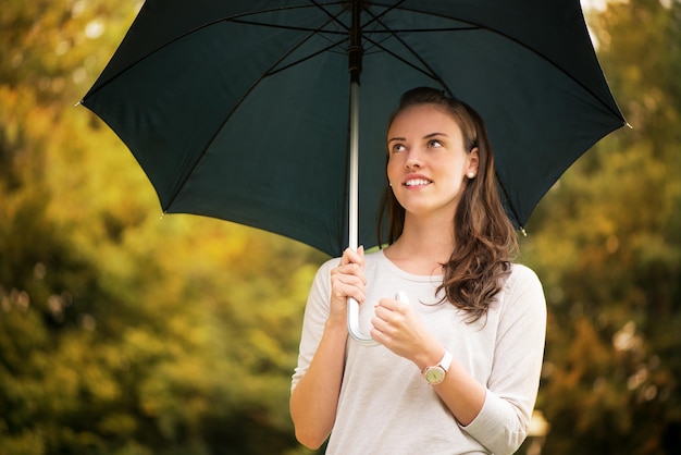 Jovem mulher bonita andando no parque chuvoso de outono com guarda-chuva.