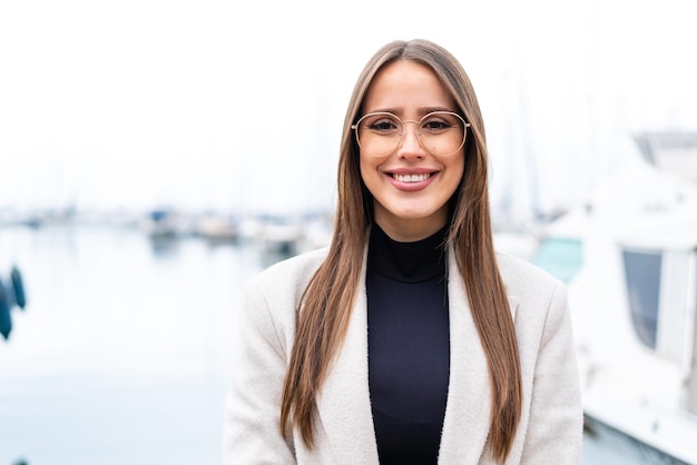 Jovem mulher bonita ao ar livre com óculos com expressão feliz