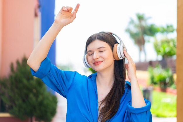 Jovem mulher bonita ao ar livre ouvindo música e dançando