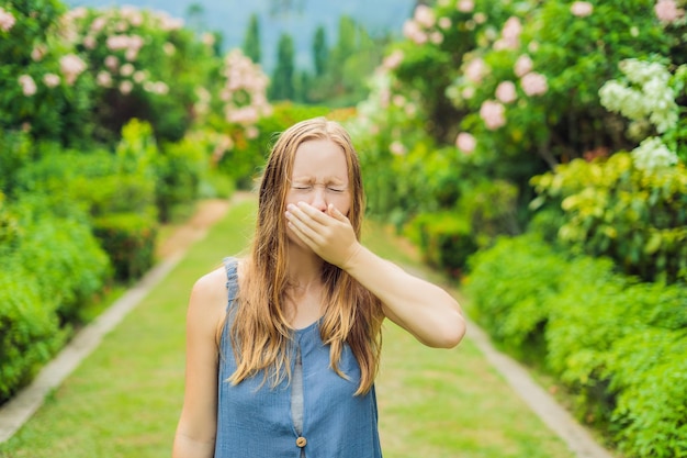 Jovem mulher bonita assoando o nariz na frente da árvore florescendo Conceito de alergia de primavera