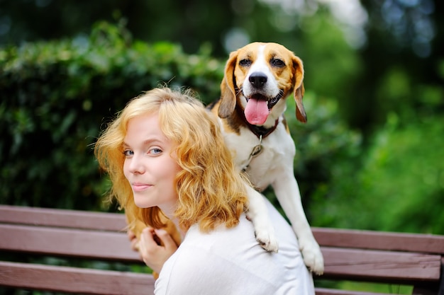 Jovem mulher bonita brincando com cachorro Beagle no parque de verão