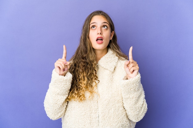 Jovem mulher bonita caucasiana apontando para cima com a boca aberta.