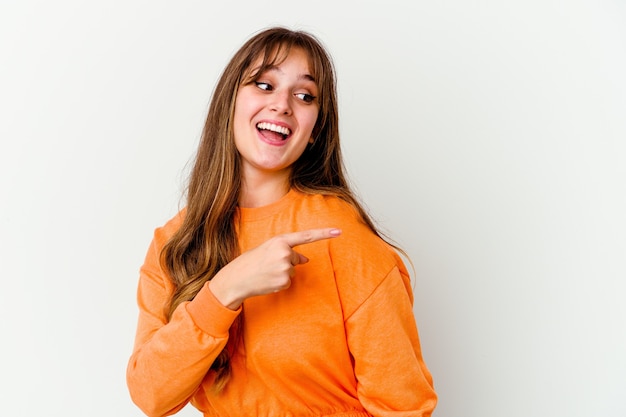 Foto jovem mulher bonita caucasiana isolada na parede branca parece de lado sorrindo, alegre e agradável.