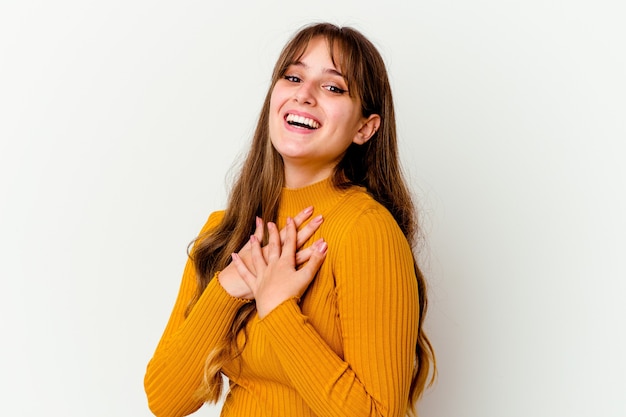 Foto jovem mulher bonita caucasiana isolada na parede branca tem uma expressão amigável, pressionando a palma da mão no peito. conceito de amor.