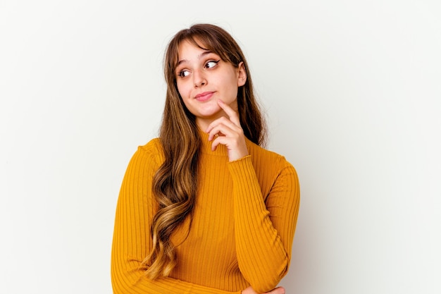 Jovem mulher bonita caucasiana isolada no branco pensando e olhando para cima, sendo reflexiva, contemplando, tendo uma fantasia.