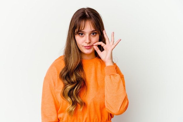 Jovem mulher bonita caucasiana isolada no fundo branco com os dedos nos lábios, mantendo um segredo.