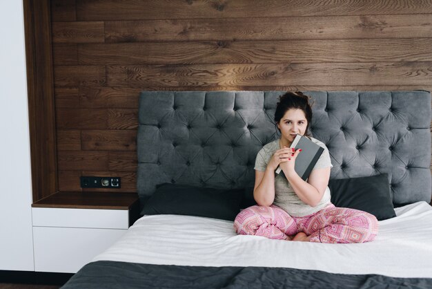 Jovem mulher bonita caucasiana, lendo um livro em sua cama, sendo confortável