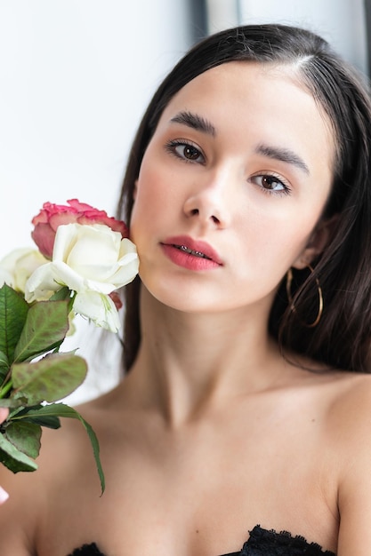 Jovem mulher bonita cheirando um monte de rosas vermelhas moda foto interior de linda mulher sorridente com cabelo escuro, segurando um grande buquê de rosas vermelhas no dia dos namorados