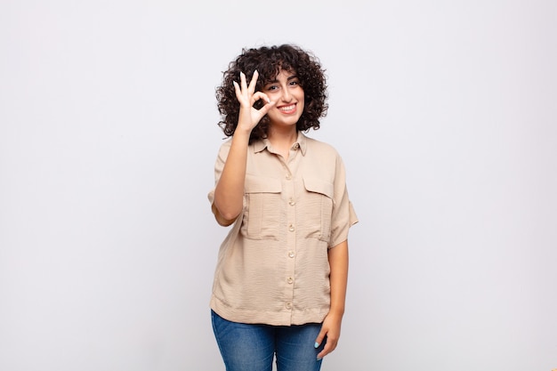 jovem mulher bonita com cabelo encaracolado. Ok gesto