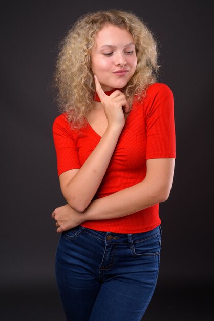 Jovem mulher bonita com cabelo loiro encaracolado contra grisalho