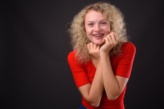 Jovem mulher bonita com cabelo loiro encaracolado contra grisalho