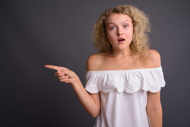 Jovem mulher bonita com cabelo loiro encaracolado contra grisalho