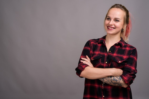 jovem mulher bonita com cabelo loiro, vestindo uma camisa xadrez vermelha em cinza