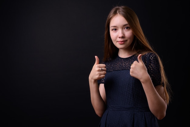 Jovem mulher bonita com cabelos castanhos compridos contra um fundo preto